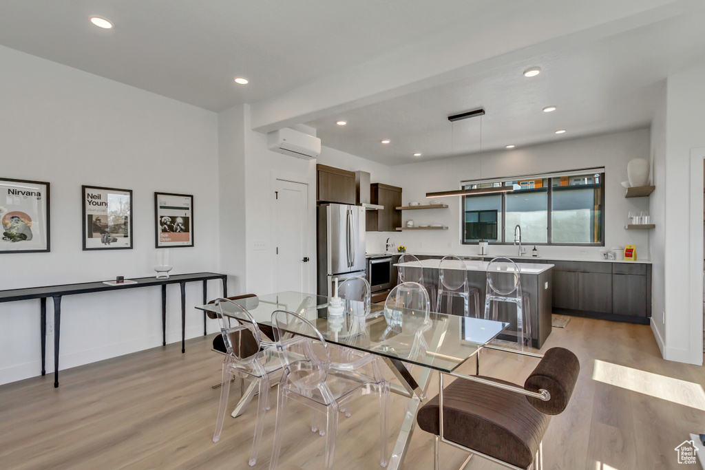 Dining space with light hardwood / wood-style flooring, a wall unit AC, and sink