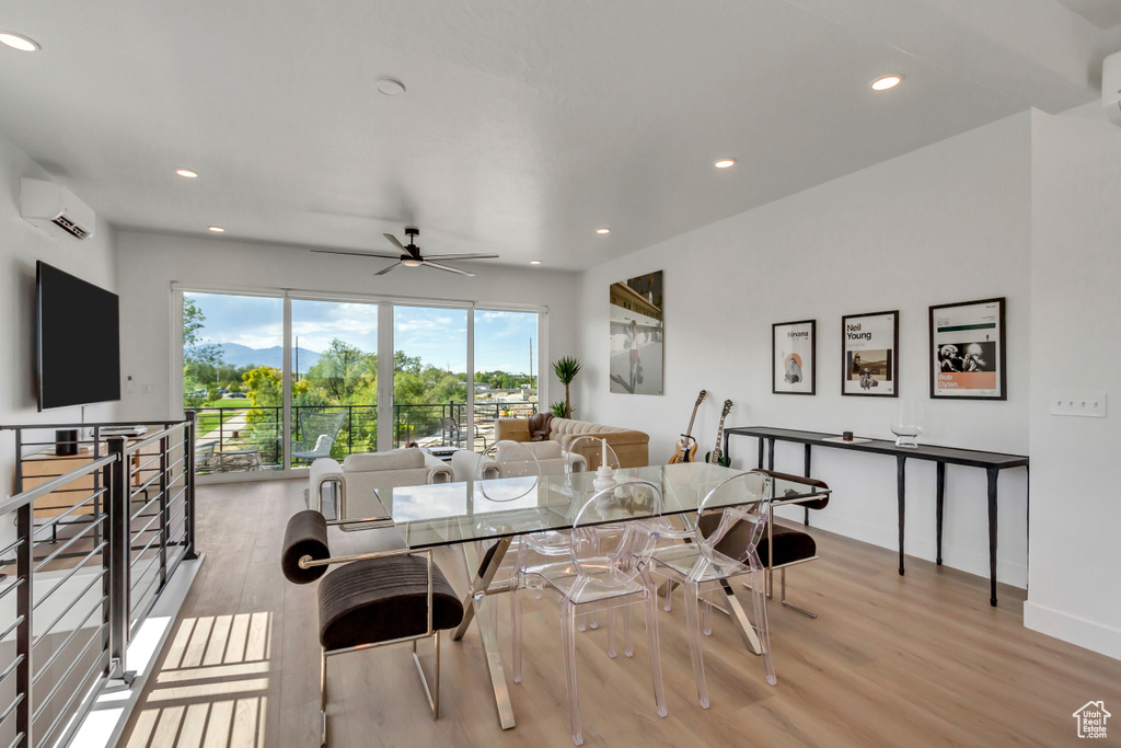 Interior space with a wall mounted AC, ceiling fan, and light wood-type flooring