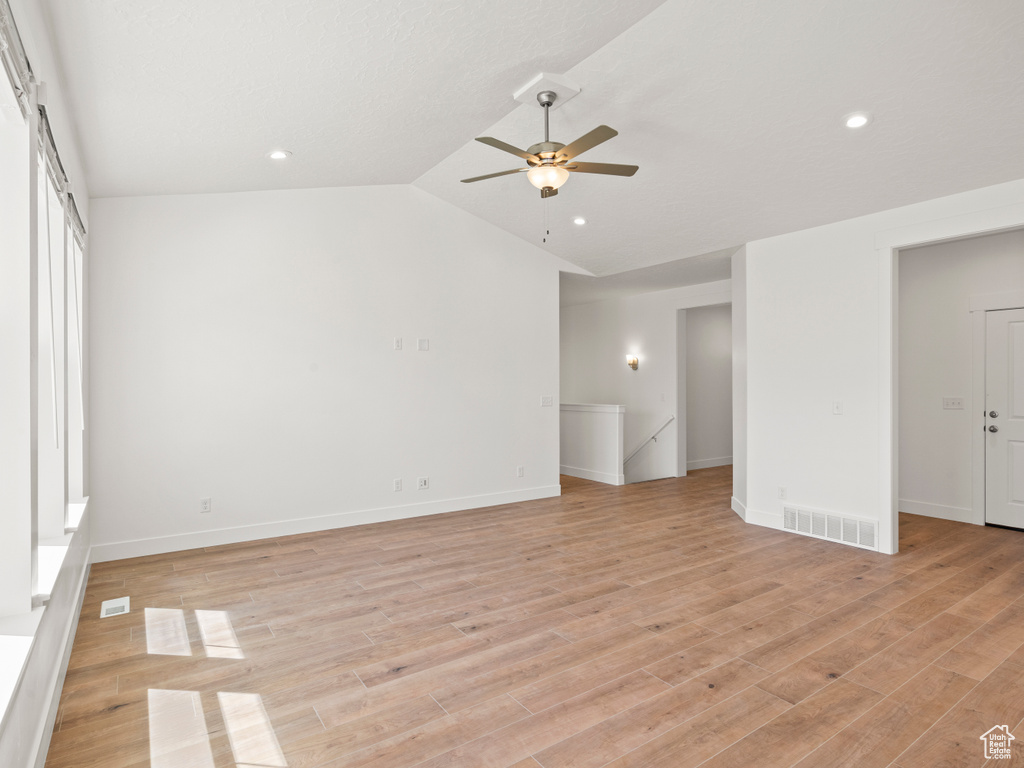 Empty room featuring lofted ceiling, light hardwood / wood-style flooring, and ceiling fan