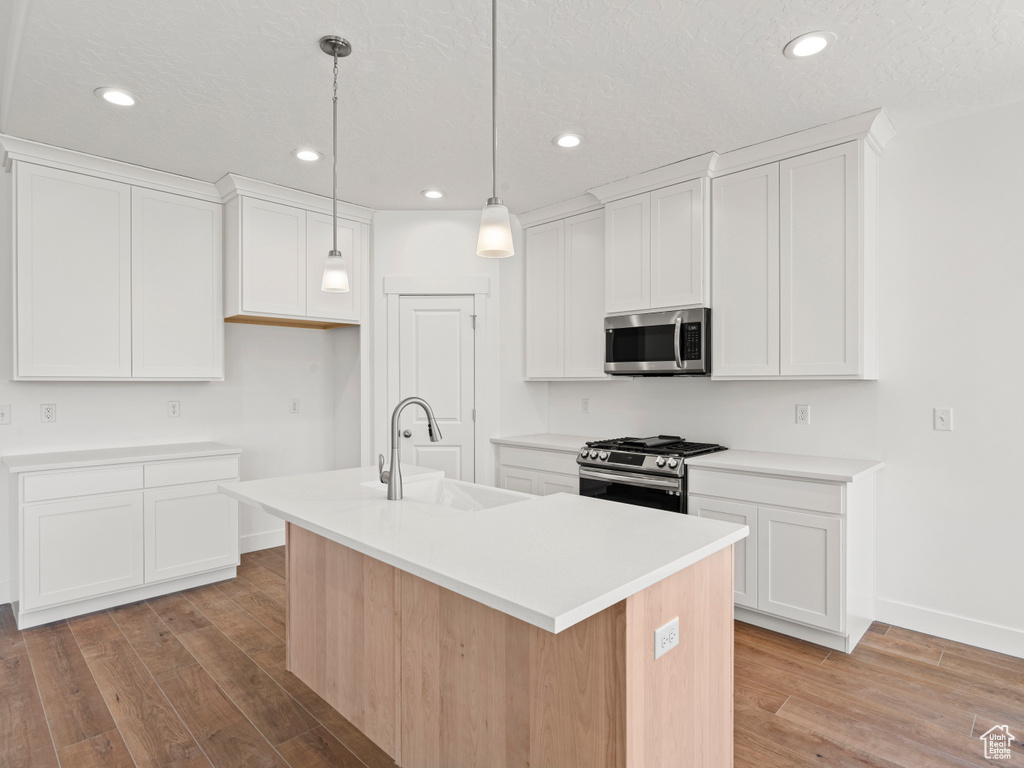 Kitchen featuring white cabinetry, stainless steel appliances, sink, a center island with sink, and light hardwood / wood-style floors