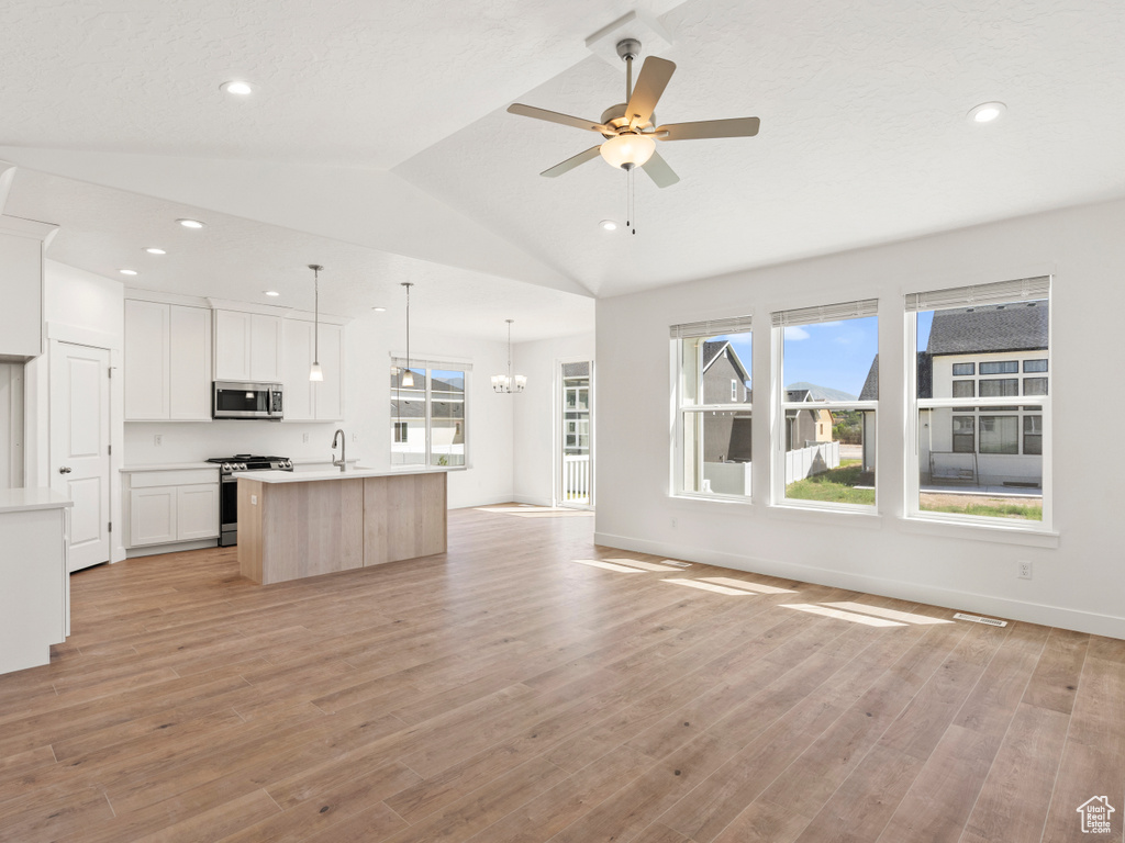 Kitchen featuring a center island with sink, light wood-type flooring, appliances with stainless steel finishes, and white cabinets