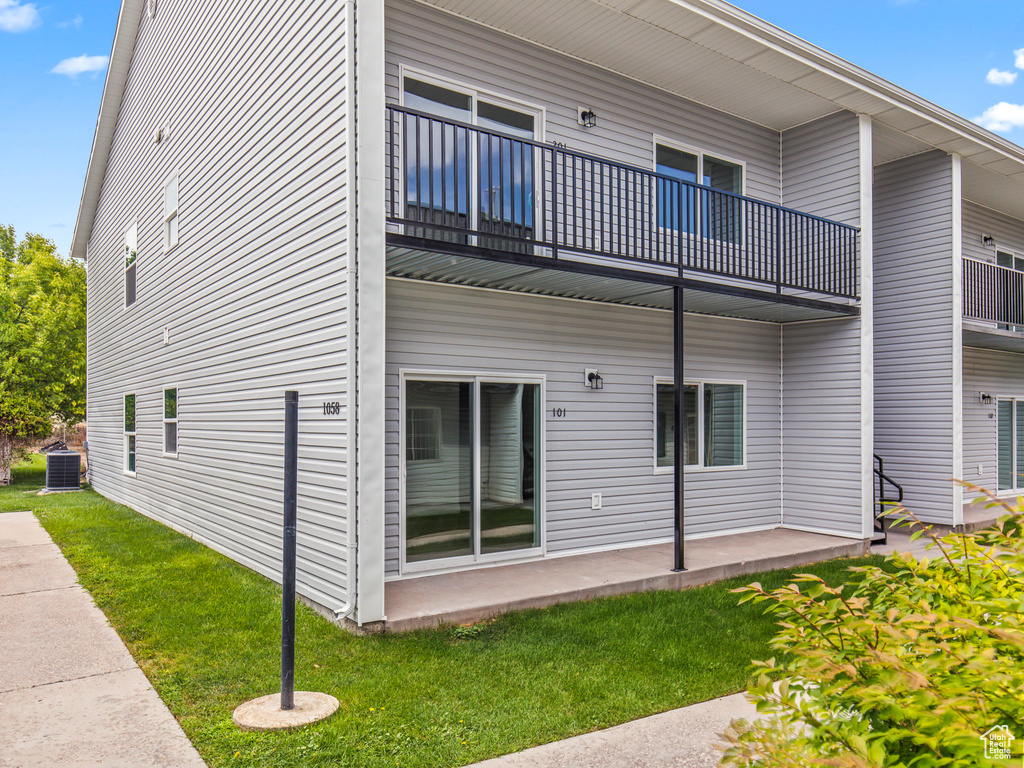 View of side of home featuring a lawn, a balcony, and central air condition unit