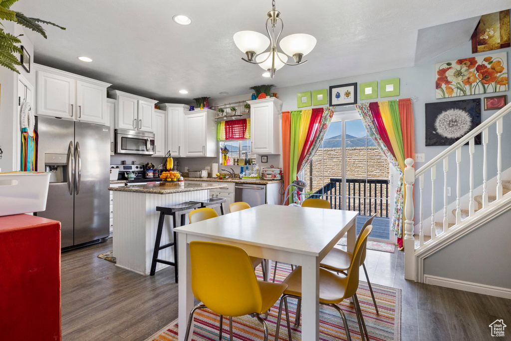 Kitchen with dark hardwood / wood-style floors, stainless steel appliances, a kitchen island, and white cabinets