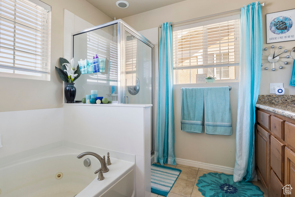 Bathroom with a healthy amount of sunlight, tile patterned floors, vanity, and independent shower and bath