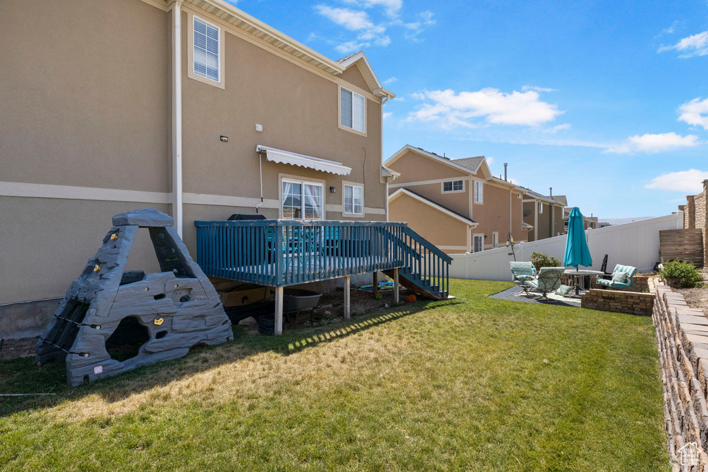 Rear view of property featuring a deck and a lawn