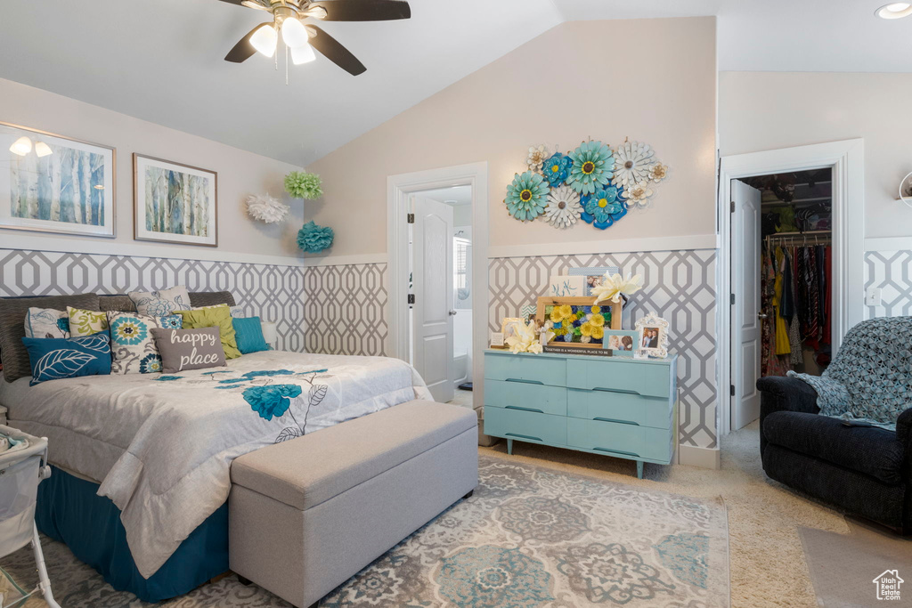 Bedroom with lofted ceiling, a spacious closet, ceiling fan, light carpet, and a closet