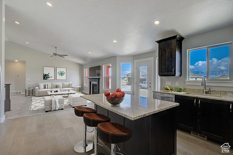 Kitchen featuring ceiling fan, sink, a kitchen island, light hardwood / wood-style flooring, and lofted ceiling