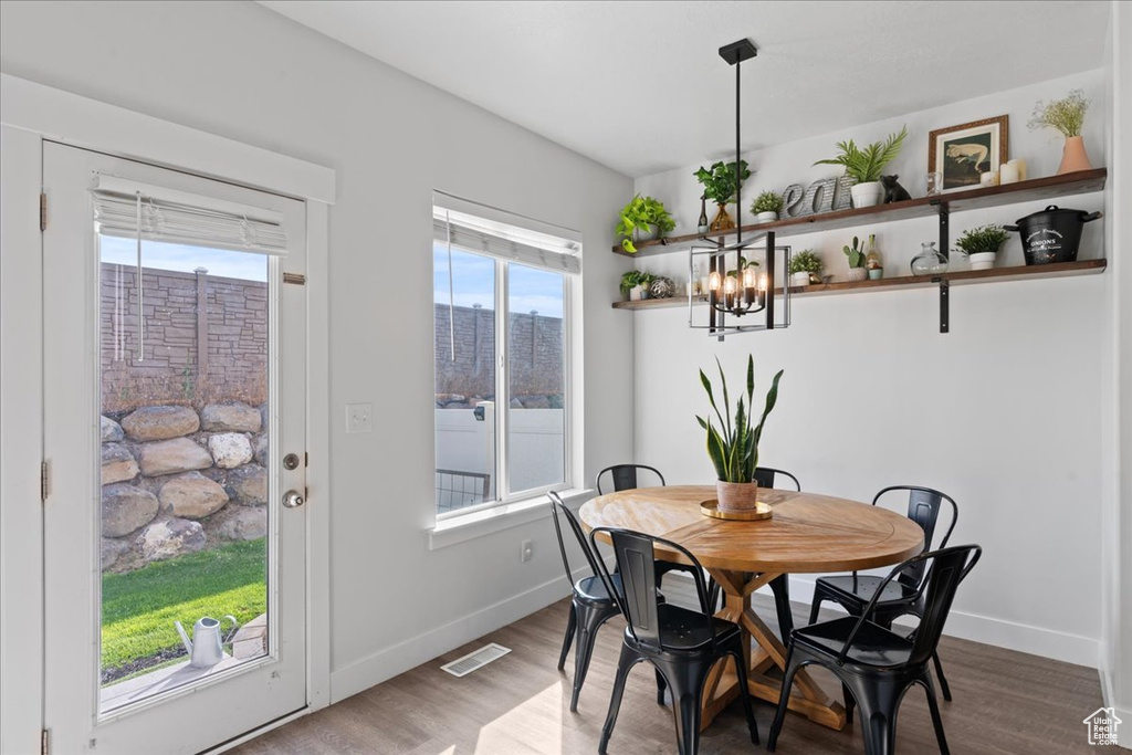 Dining room featuring a healthy amount of sunlight, a notable chandelier, and wood-type flooring