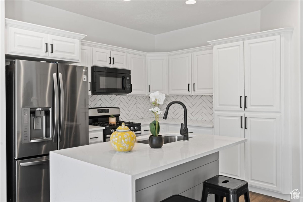 Kitchen with appliances with stainless steel finishes, white cabinets, sink, backsplash, and light hardwood / wood-style floors