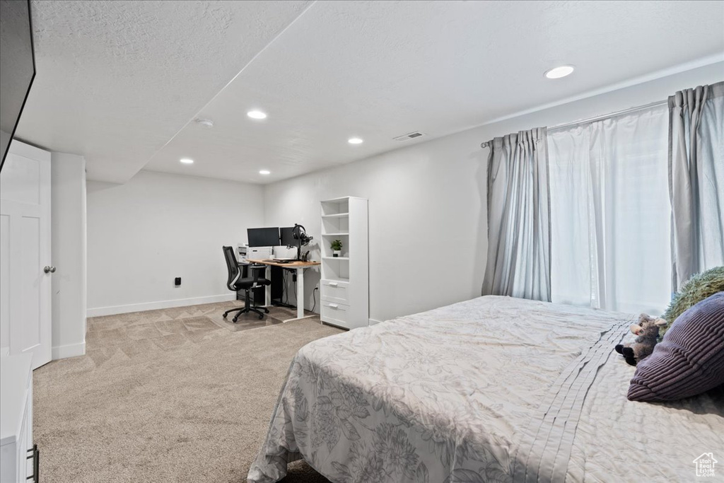 Bedroom with a textured ceiling and light colored carpet