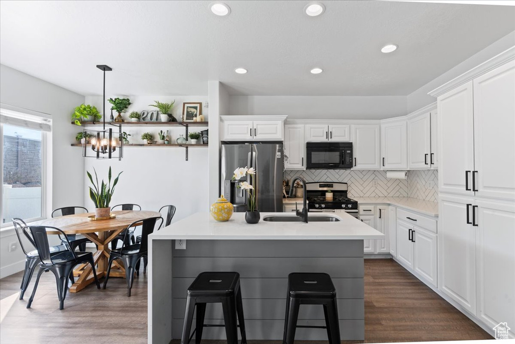 Kitchen with dark hardwood / wood-style floors, stainless steel appliances, backsplash, and white cabinets