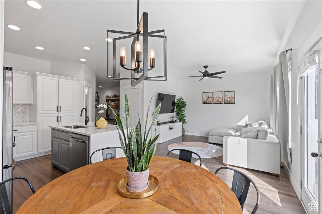 Dining space with ceiling fan with notable chandelier, hardwood / wood-style floors, and sink