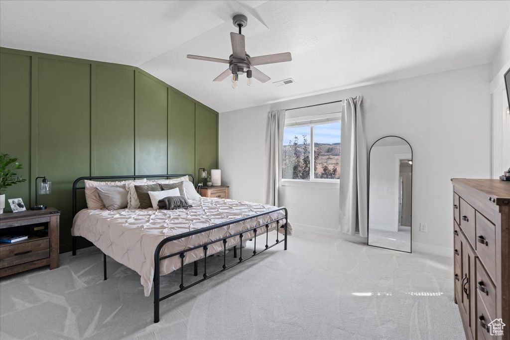 Bedroom with light colored carpet, vaulted ceiling, and ceiling fan