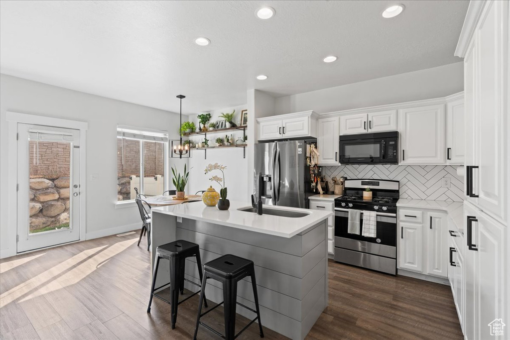 Kitchen with decorative backsplash, appliances with stainless steel finishes, dark hardwood / wood-style flooring, and white cabinets