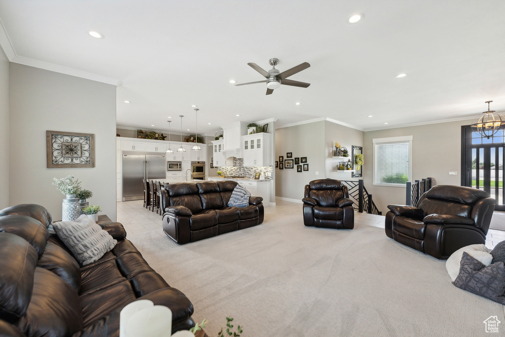 Carpeted living room featuring ceiling fan and crown molding