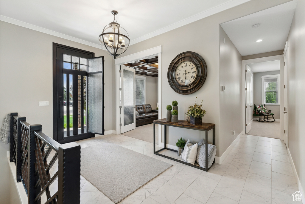 Foyer entrance featuring light carpet, a notable chandelier, and crown molding