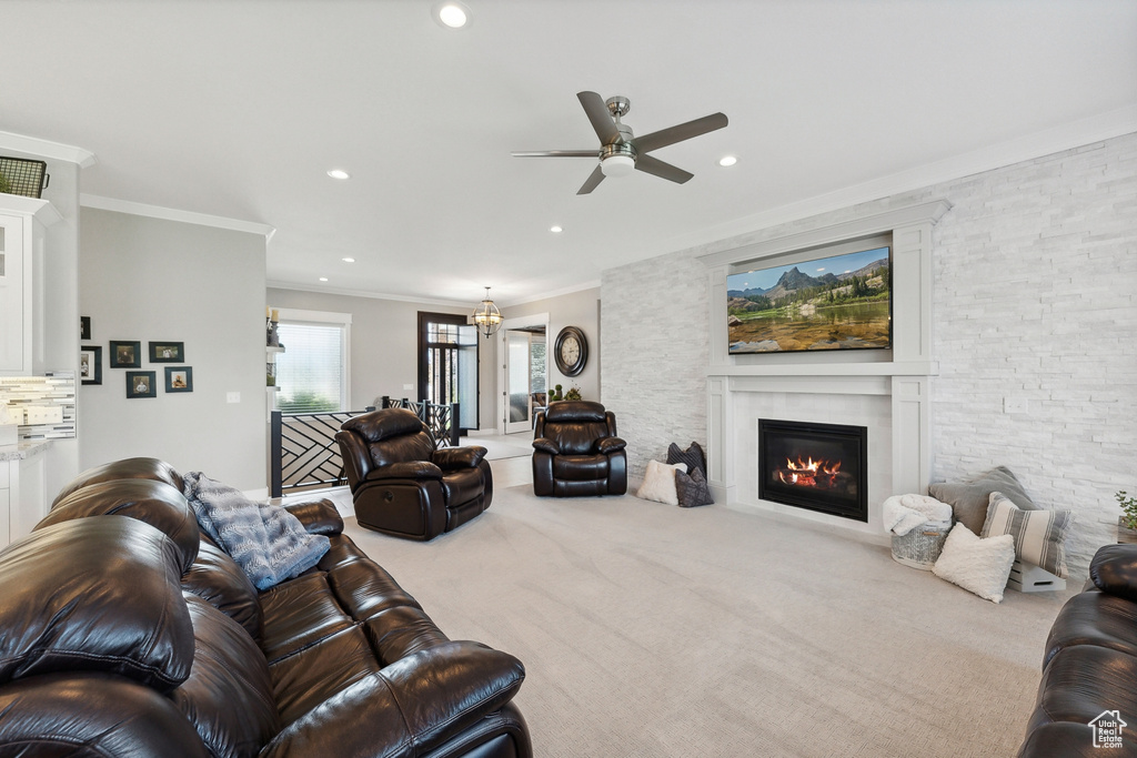 Carpeted living room with ceiling fan with notable chandelier and ornamental molding