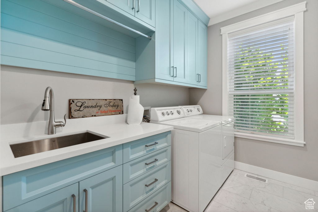 Clothes washing area with plenty of natural light, sink, light tile patterned flooring, and washing machine and clothes dryer