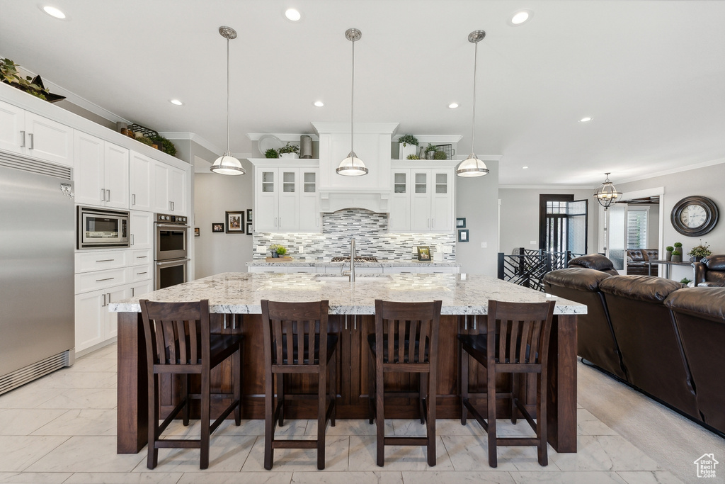 Kitchen featuring a breakfast bar area, tasteful backsplash, light tile patterned floors, and built in appliances