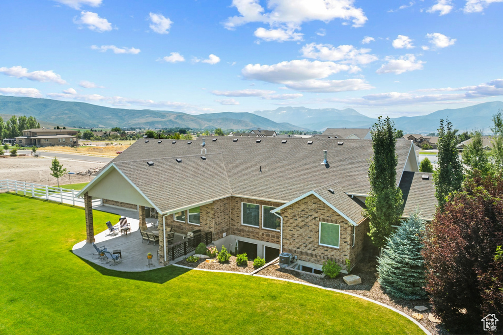 Rear view of property with a mountain view, central AC, a patio area, and a lawn