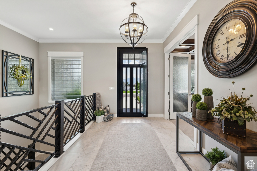 Foyer entrance featuring light tile patterned flooring, crown molding, and a chandelier