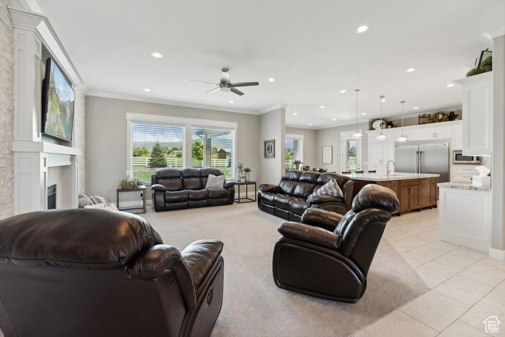 Tiled living room with ornamental molding, sink, and ceiling fan