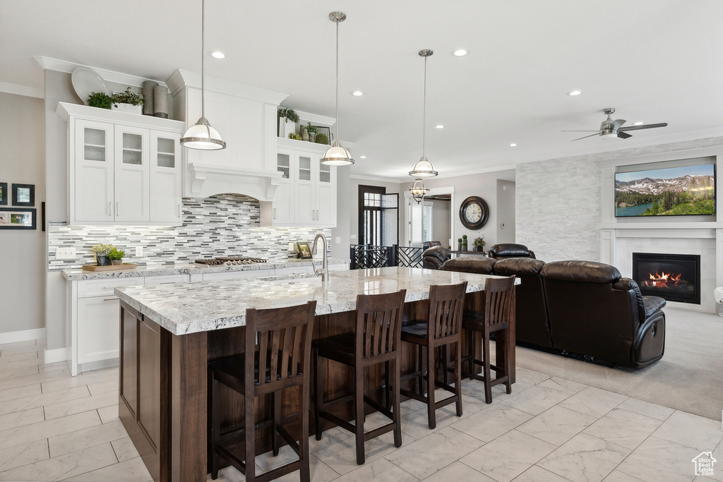 Kitchen with white cabinets, a breakfast bar, hanging light fixtures, and ceiling fan