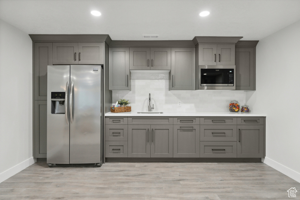 Kitchen featuring gray cabinetry, light hardwood / wood-style flooring, and stainless steel appliances