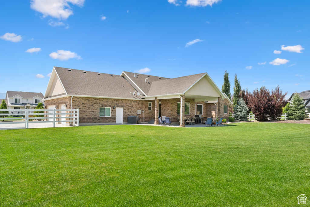 Back of house with central AC, a patio area, and a lawn