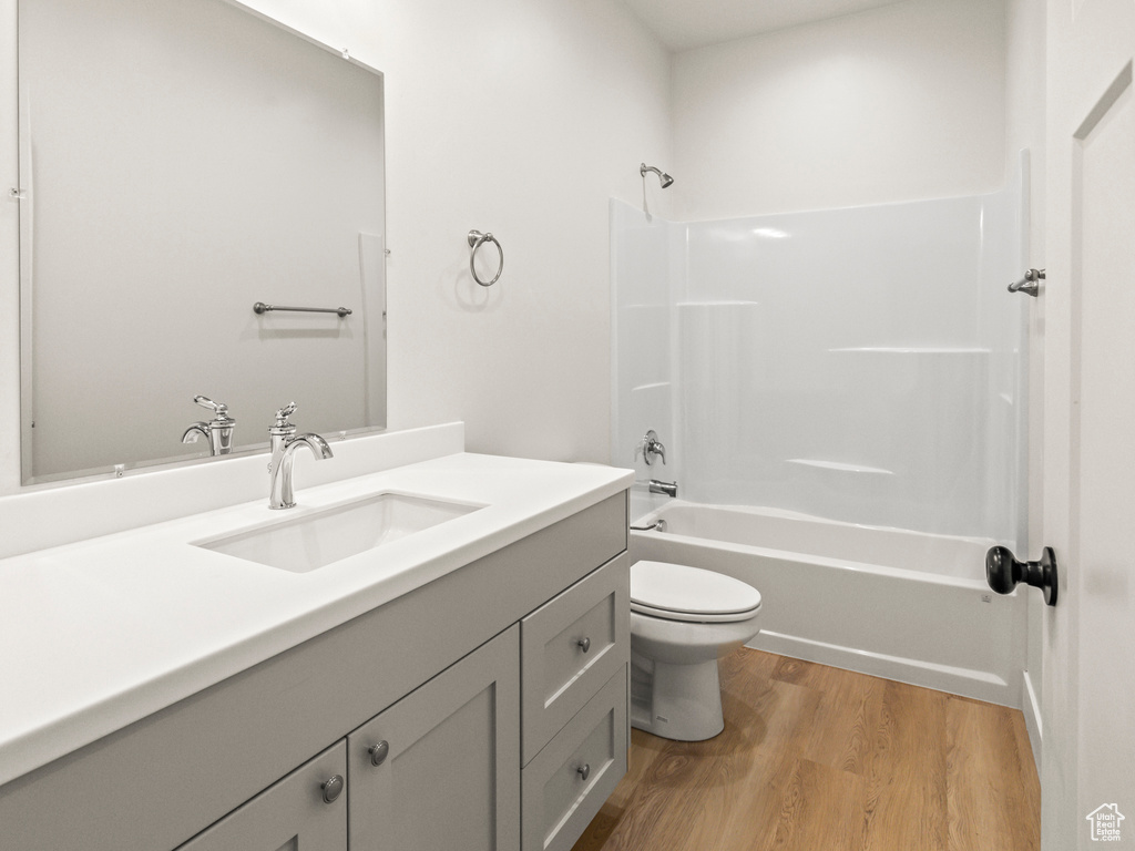 Full bathroom featuring wood-type flooring, toilet, vanity, and tub / shower combination