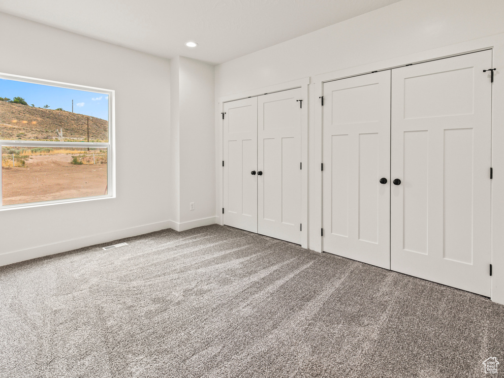 Unfurnished bedroom with two closets and carpet flooring