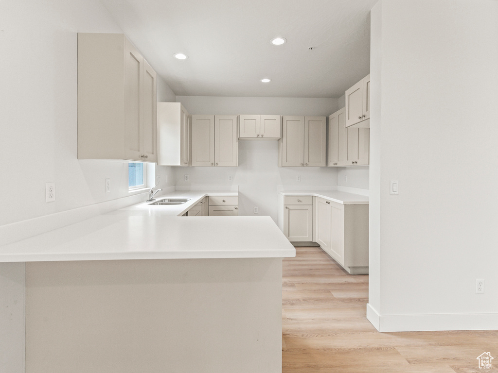 Kitchen featuring sink, kitchen peninsula, and light wood-type flooring