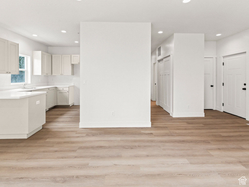 Kitchen with white cabinets, sink, and light wood-type flooring