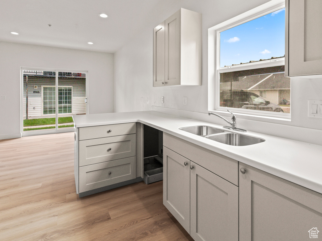 Kitchen featuring gray cabinets, sink, wood-type flooring, and kitchen peninsula