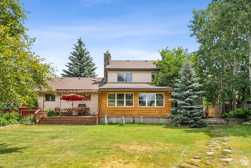 Rear view of house with a deck and a lawn