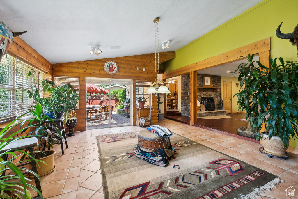 Sunroom with a stone fireplace, vaulted ceiling, and plenty of natural light