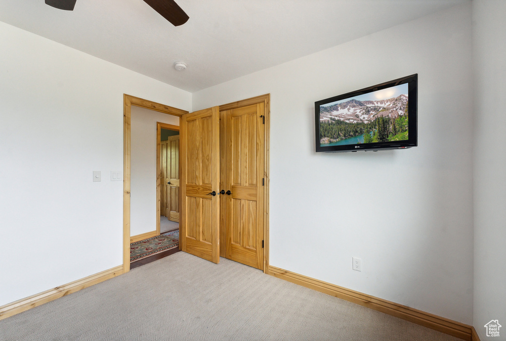 Unfurnished bedroom with ceiling fan and light colored carpet