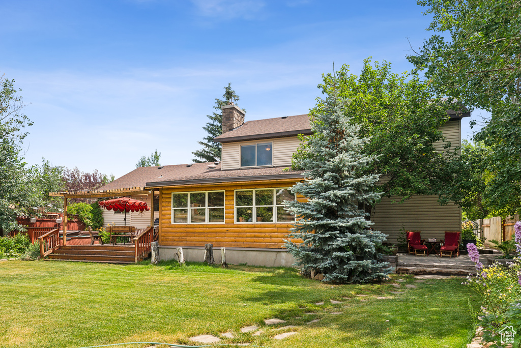 Back of house featuring a wooden deck, a yard, and a pergola