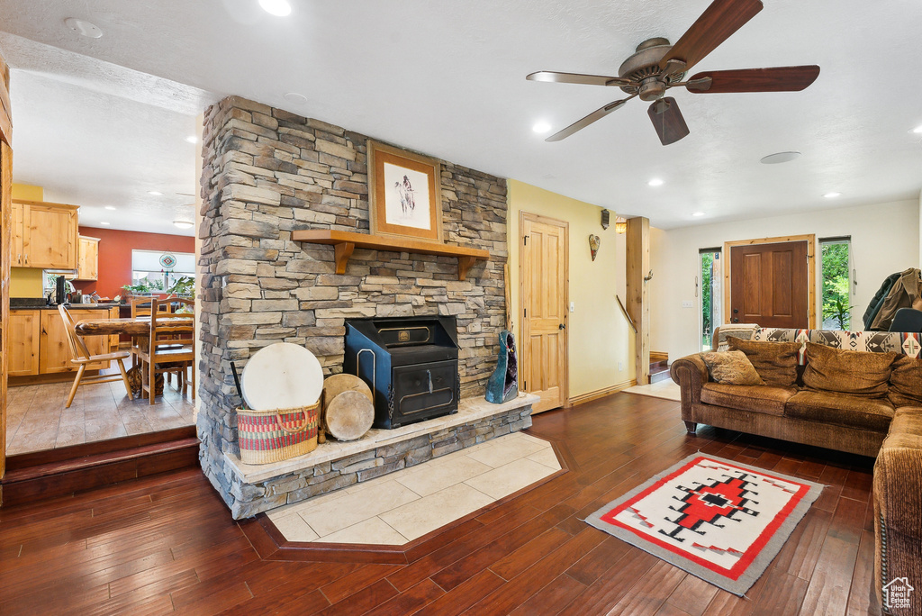 Living room with a wood stove, hardwood / wood-style floors, a fireplace, and ceiling fan