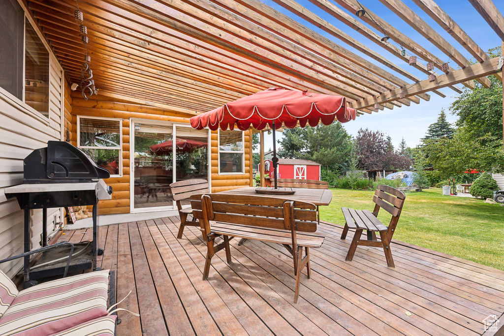 Deck featuring a pergola and a lawn