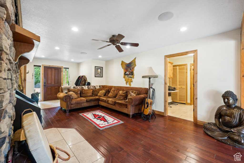 Living room with a stone fireplace, tile patterned flooring, and ceiling fan