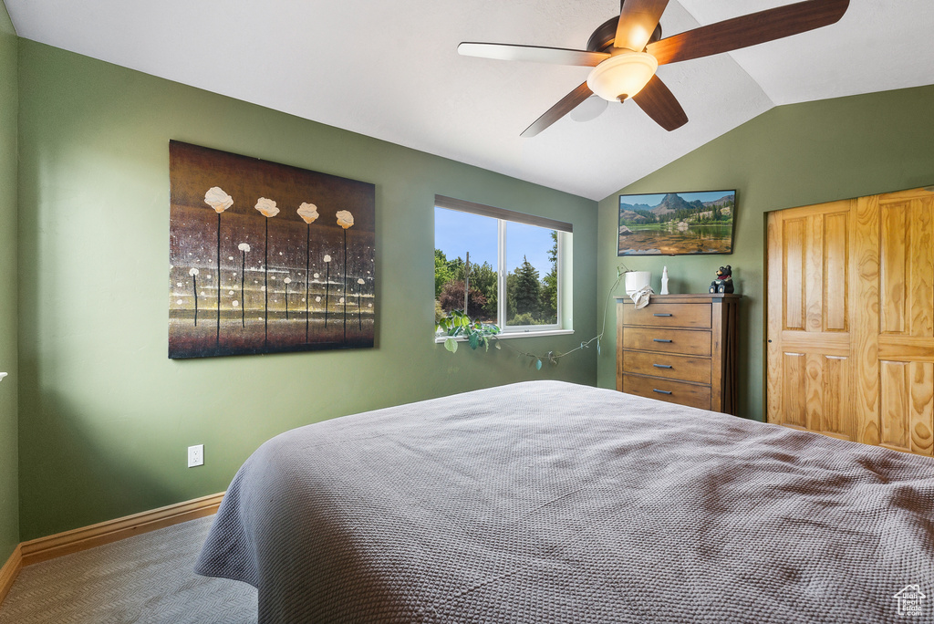 Carpeted bedroom with ceiling fan and lofted ceiling