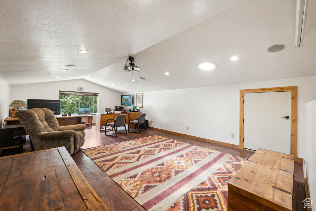 Living room featuring a textured ceiling, lofted ceiling, and hardwood / wood-style floors