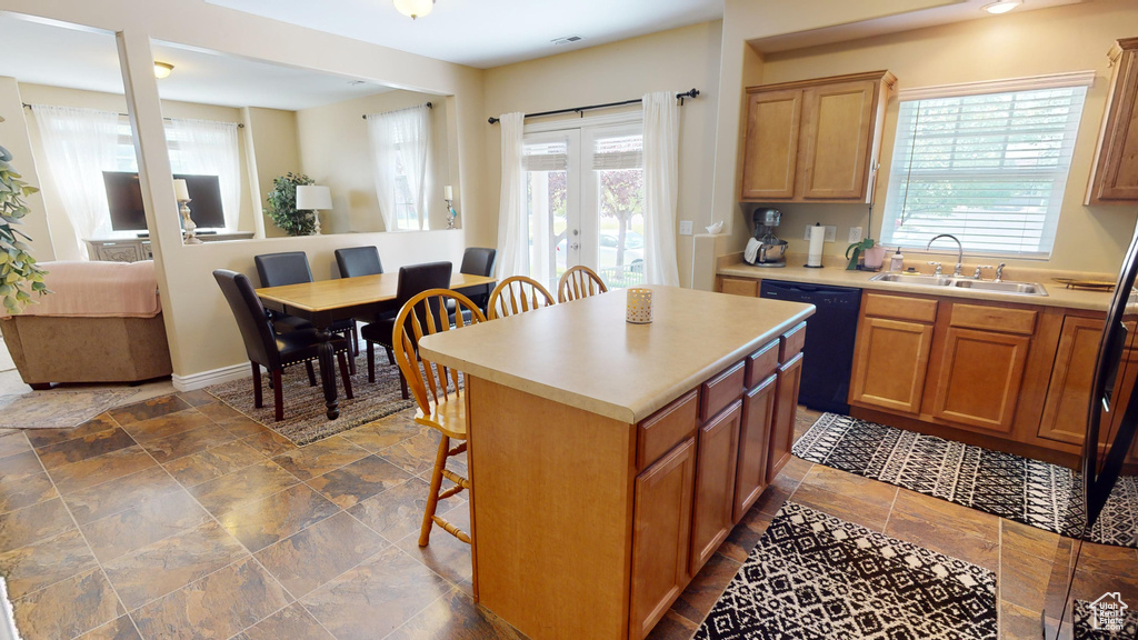 Kitchen featuring a wealth of natural light, black dishwasher, dark tile patterned flooring, and a kitchen island