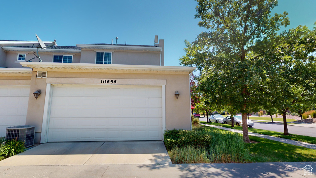 View of front of home with cooling unit and a garage