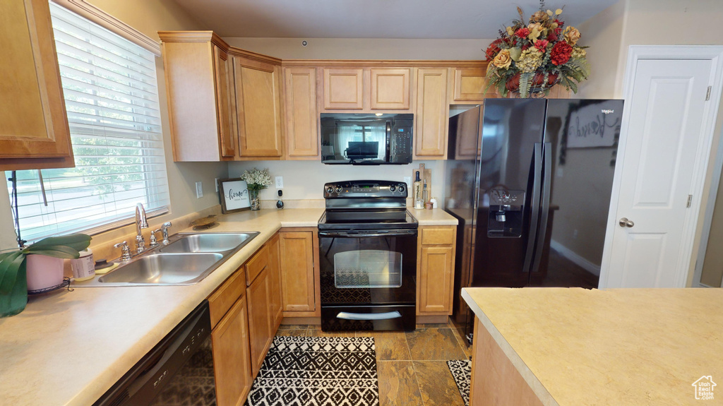 Kitchen featuring light brown cabinetry, sink, black appliances, and light tile patterned floors