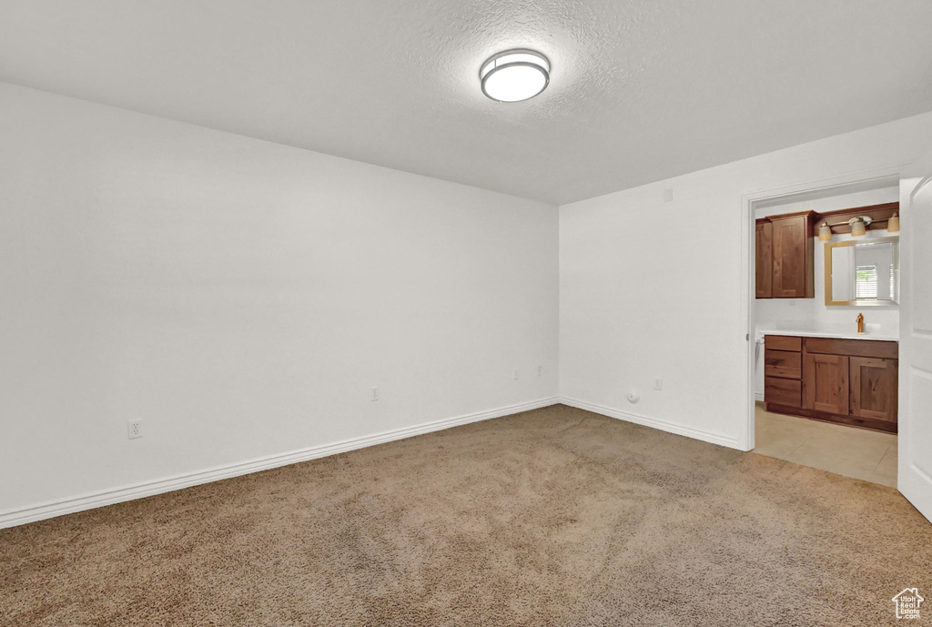 Unfurnished bedroom featuring ensuite bath and light carpet