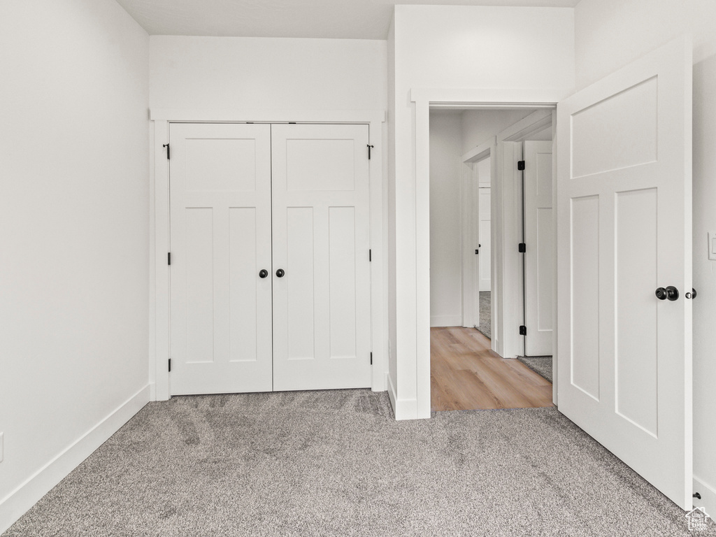 Unfurnished bedroom featuring light carpet and a closet