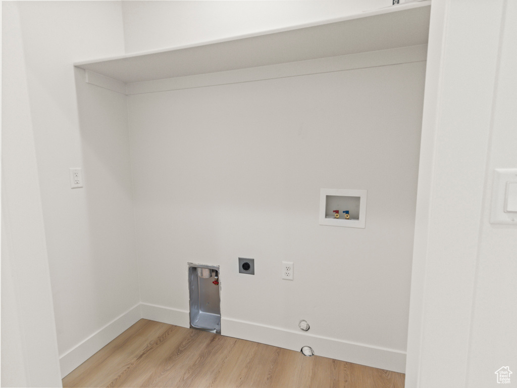 Laundry area with hookup for a washing machine, gas dryer hookup, light hardwood / wood-style floors, and hookup for an electric dryer