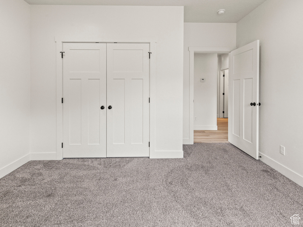 Unfurnished bedroom with light colored carpet and a closet